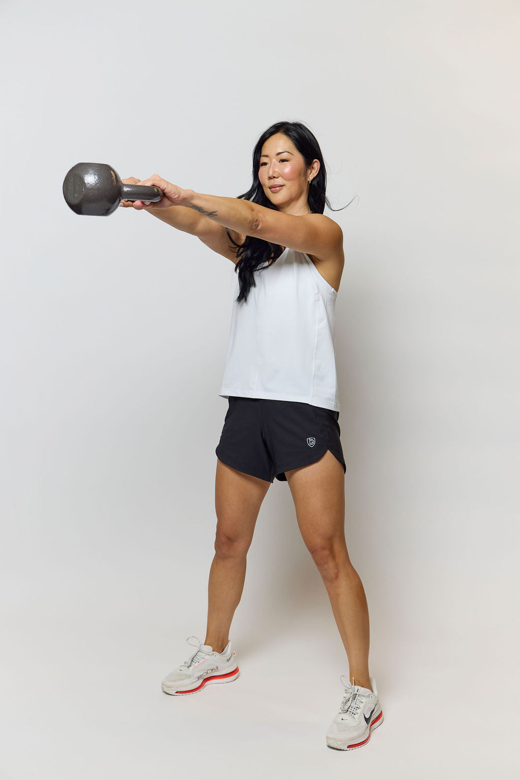Woman exercising with a kettlebell against a white background