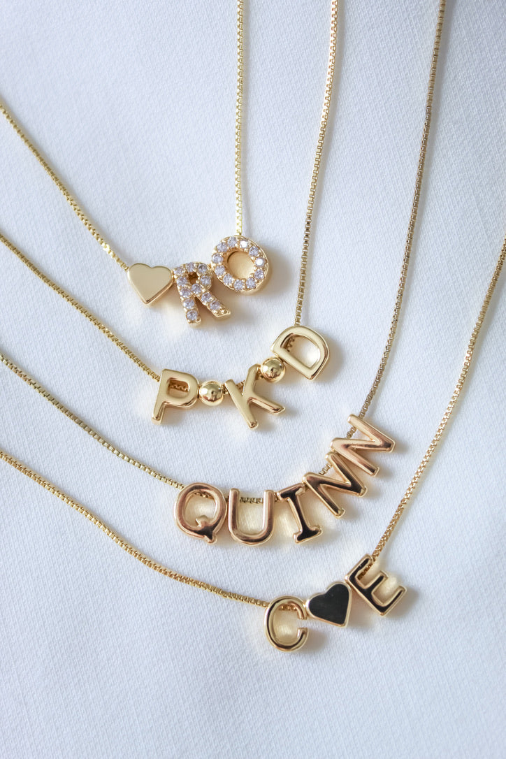 Gold necklaces with various names on a white background