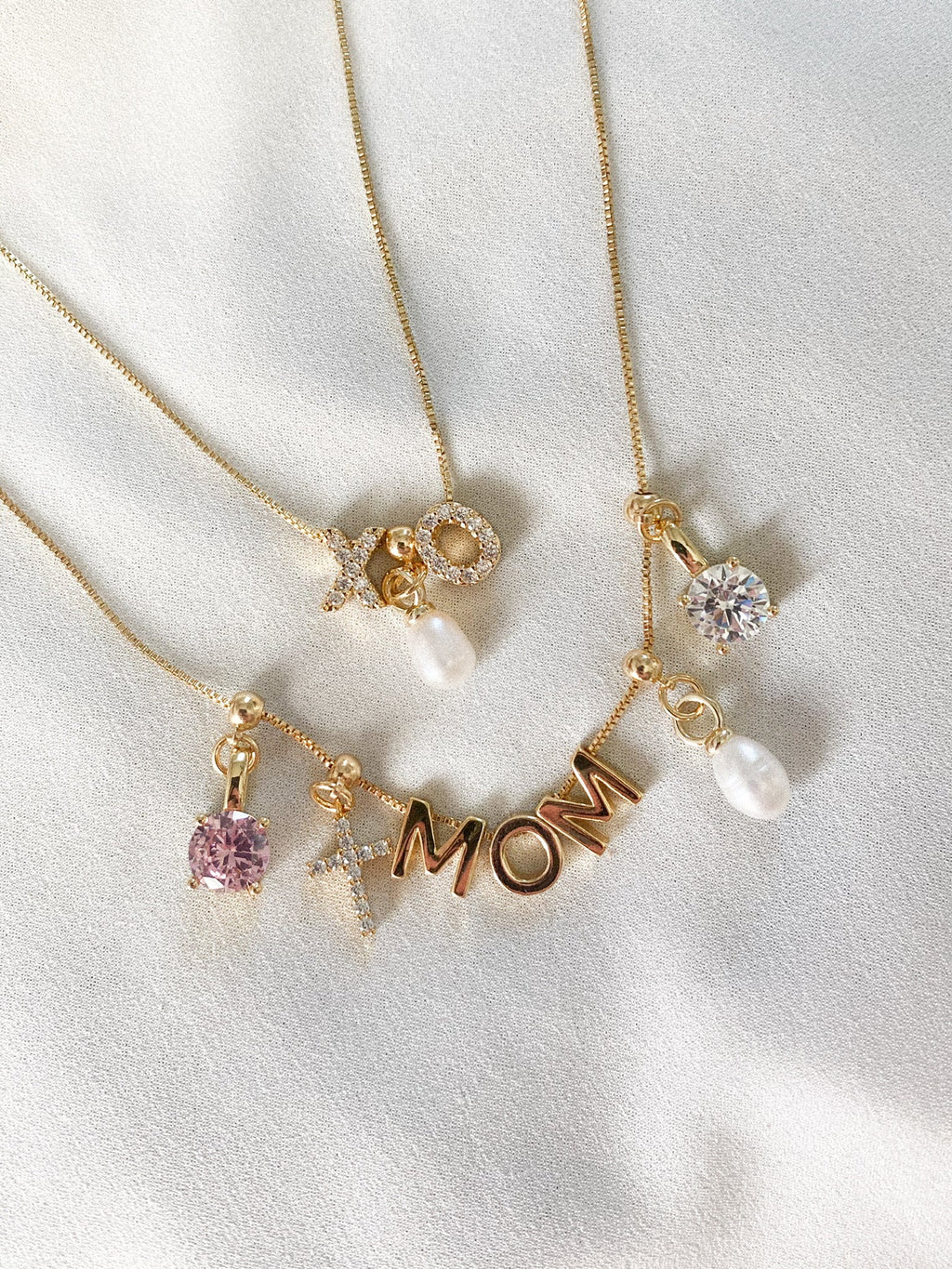 Gold necklaces with 'MOM' charm and various pendants on a white background