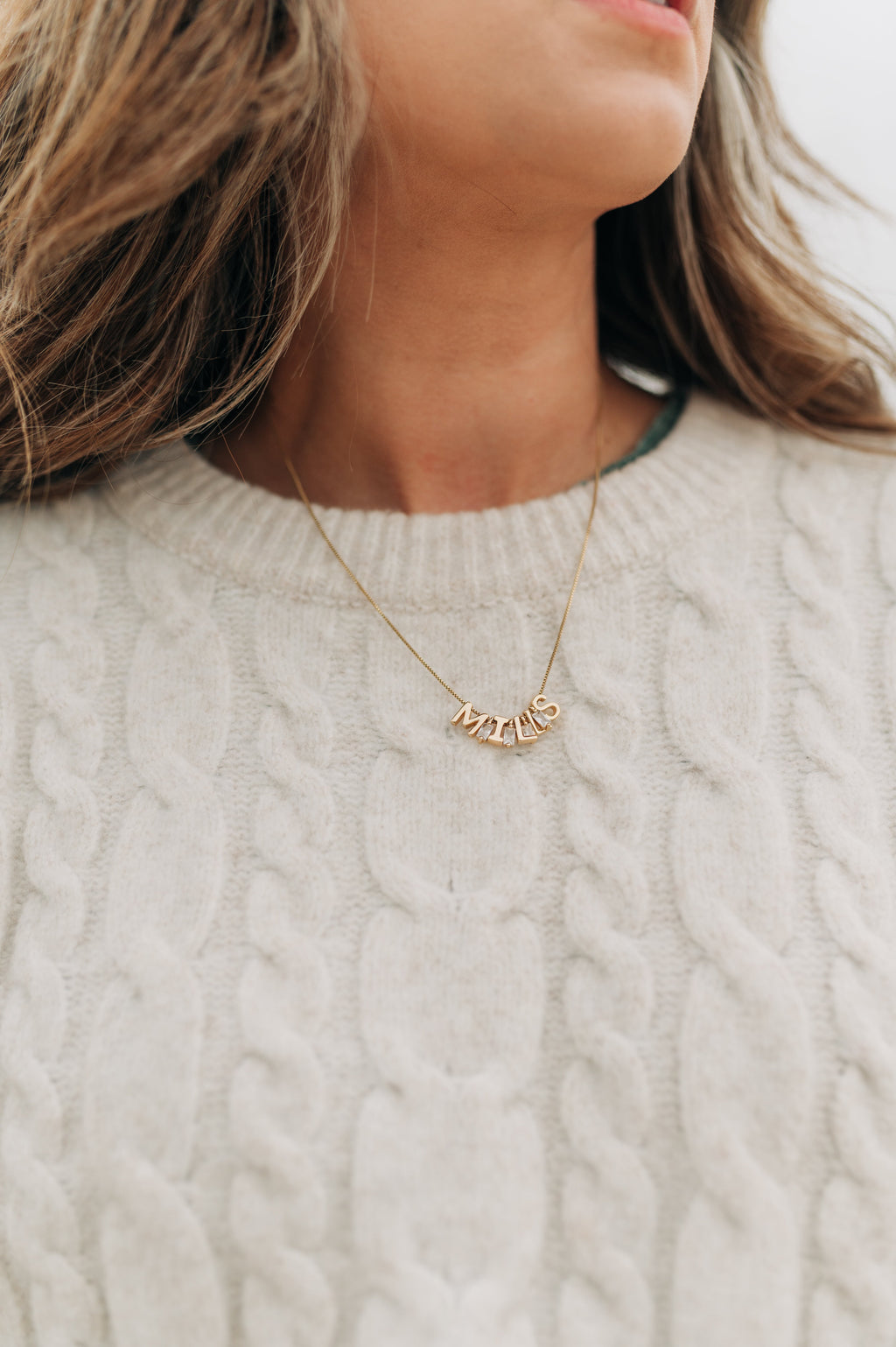 Necklace with 'MILAN' pendant worn by a person in a light sweater