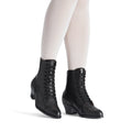 Black lace-up boots worn with white tights on a white background