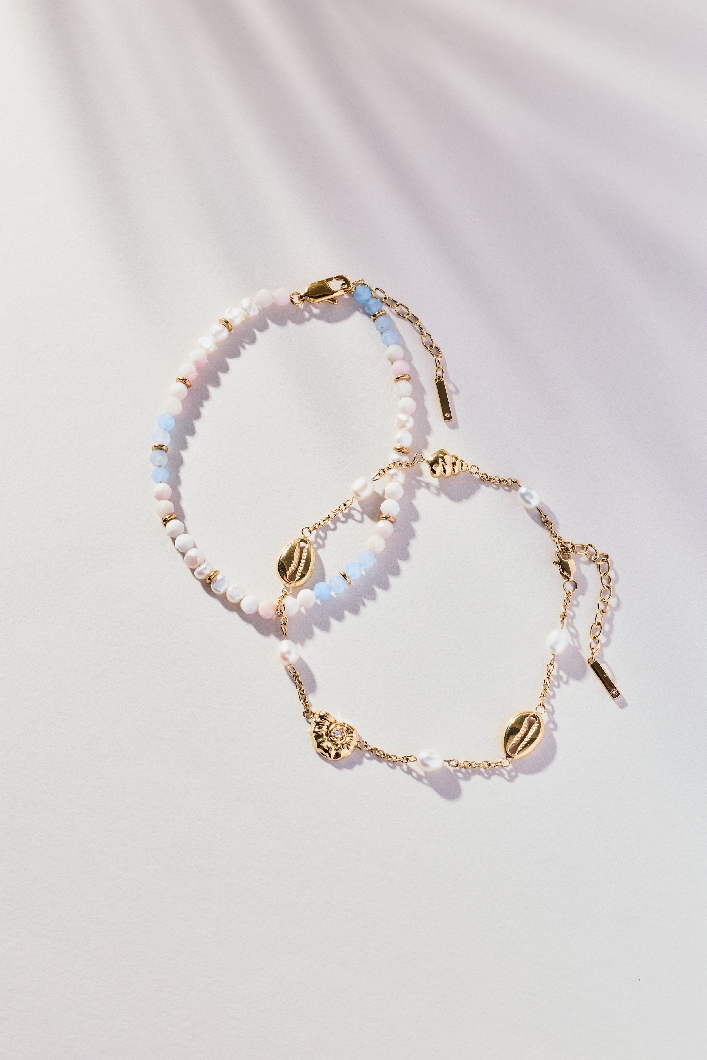 Two beaded bracelets with gold accents on a light background