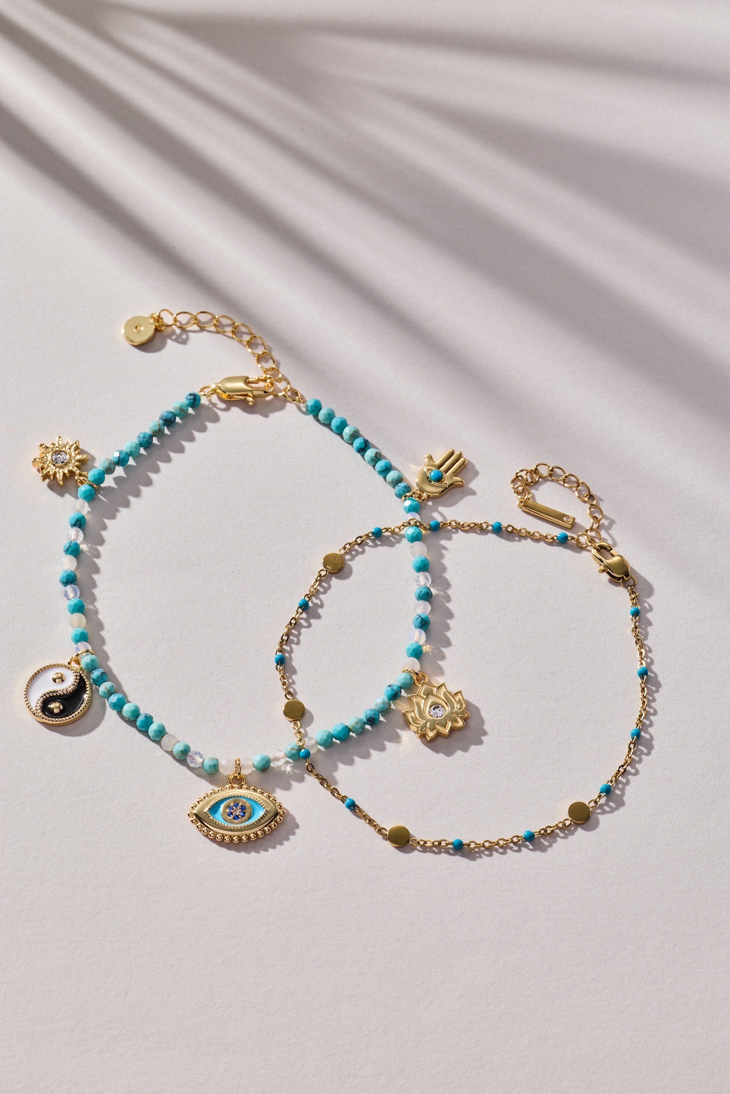Turquoise beaded bracelet with gold accents and charms on a light background