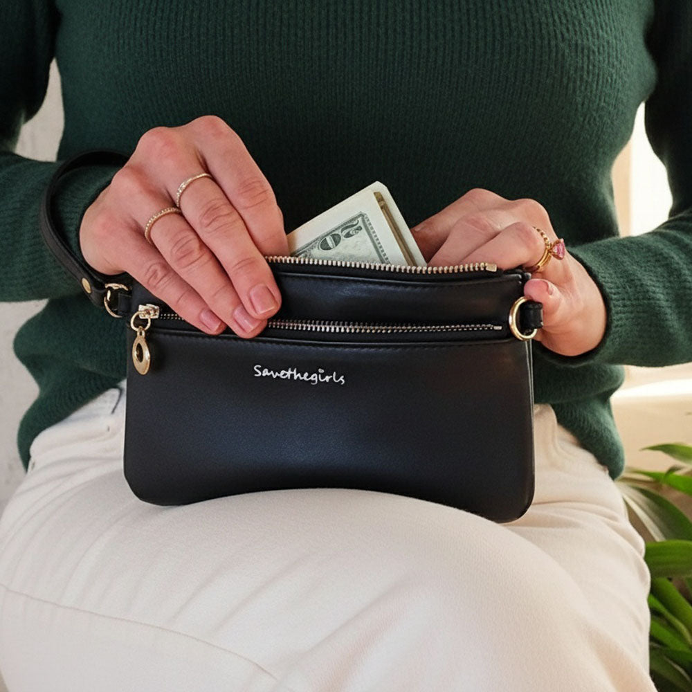 Person holding a black handbag with 'SaveTheGirls' branding, opening it to reveal money.