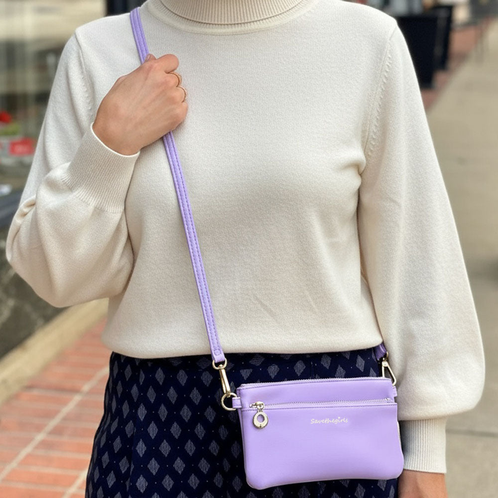 Person wearing a light-colored sweater and dark patterned skirt with a purple handbag.