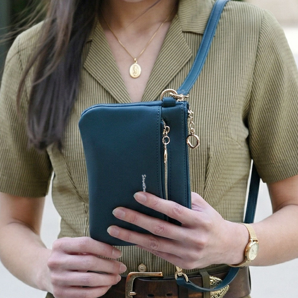 Person holding a teal handbag with gold accents