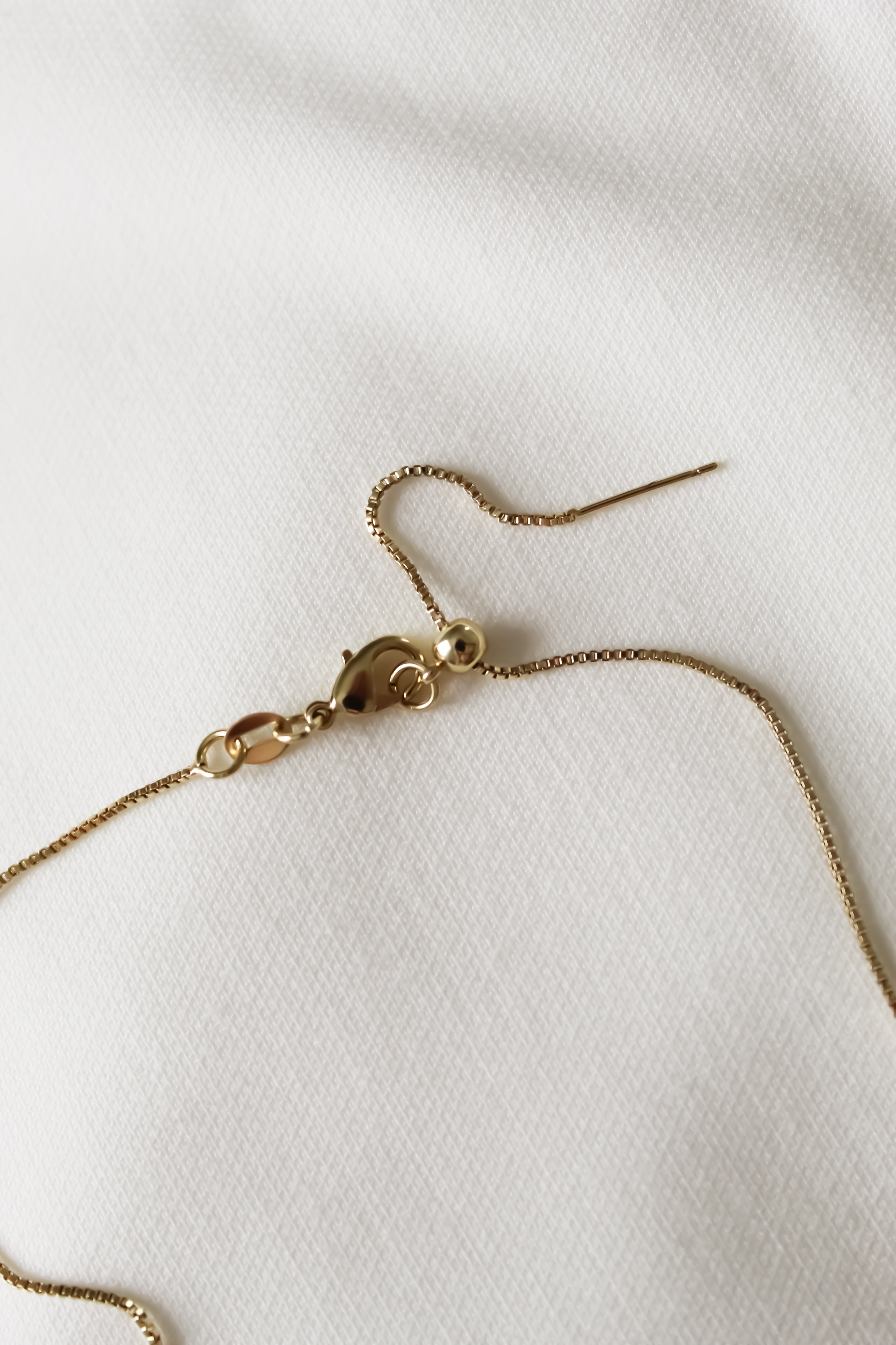 Gold necklace on a white fabric background