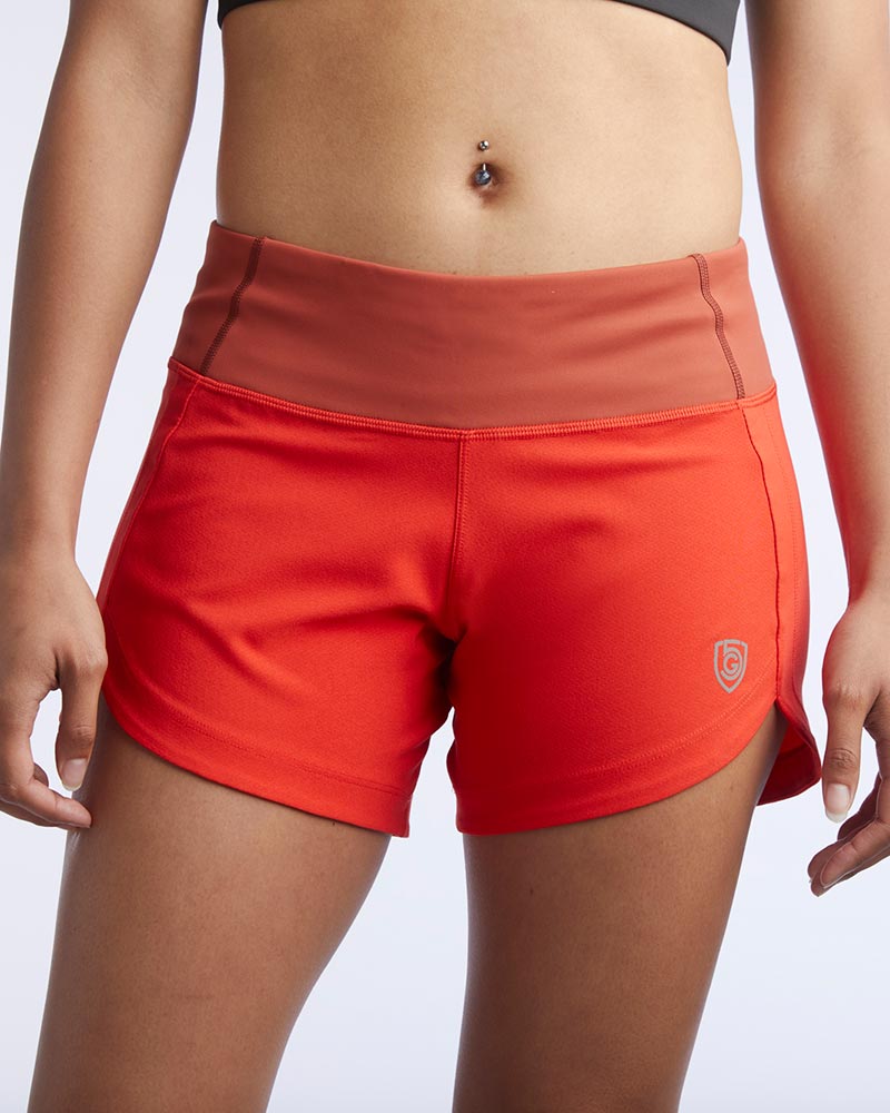 Red athletic shorts with a brown waistband on a white background