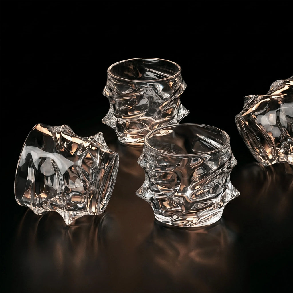 Set of four textured glass tumblers on a reflective surface with a black background