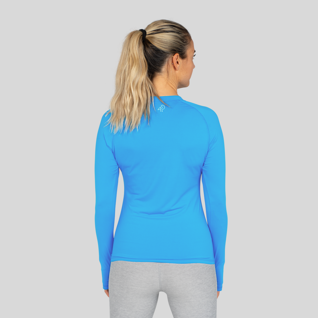 Woman wearing a blue long-sleeve athletic shirt on a gray background