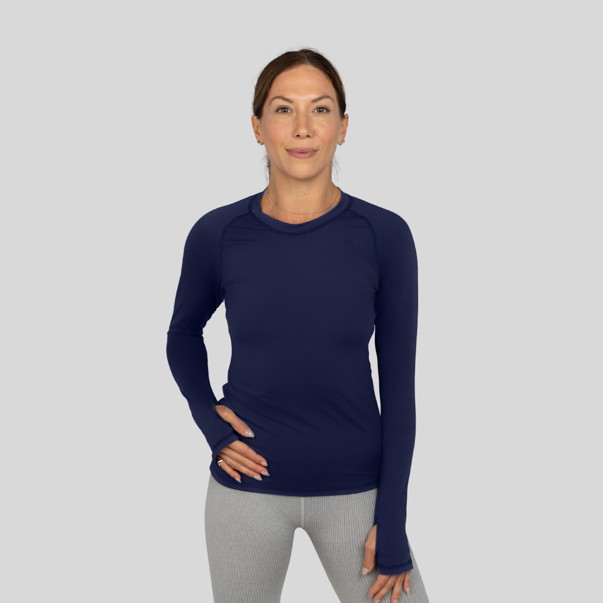 Woman wearing a navy long-sleeve shirt and gray pants on a light gray background