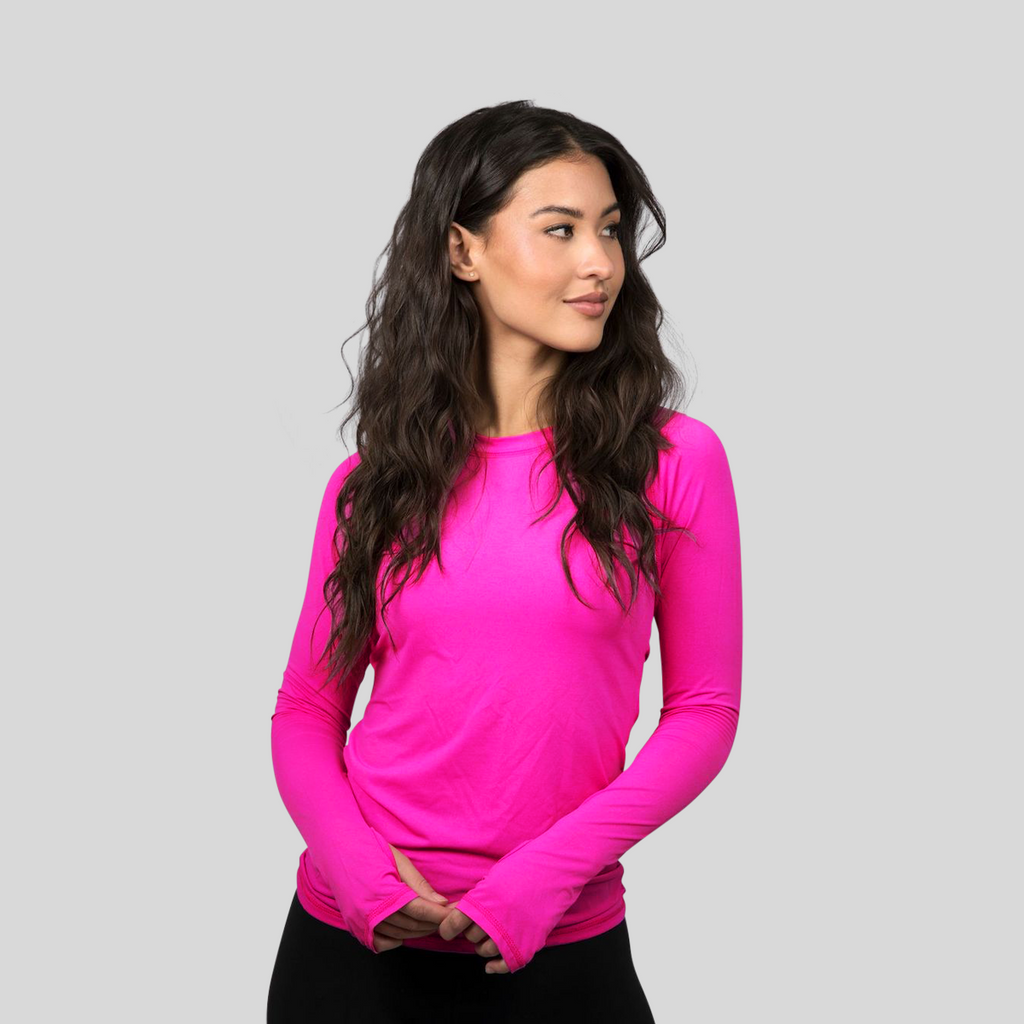 Woman wearing a bright pink long-sleeve top against a gray background
