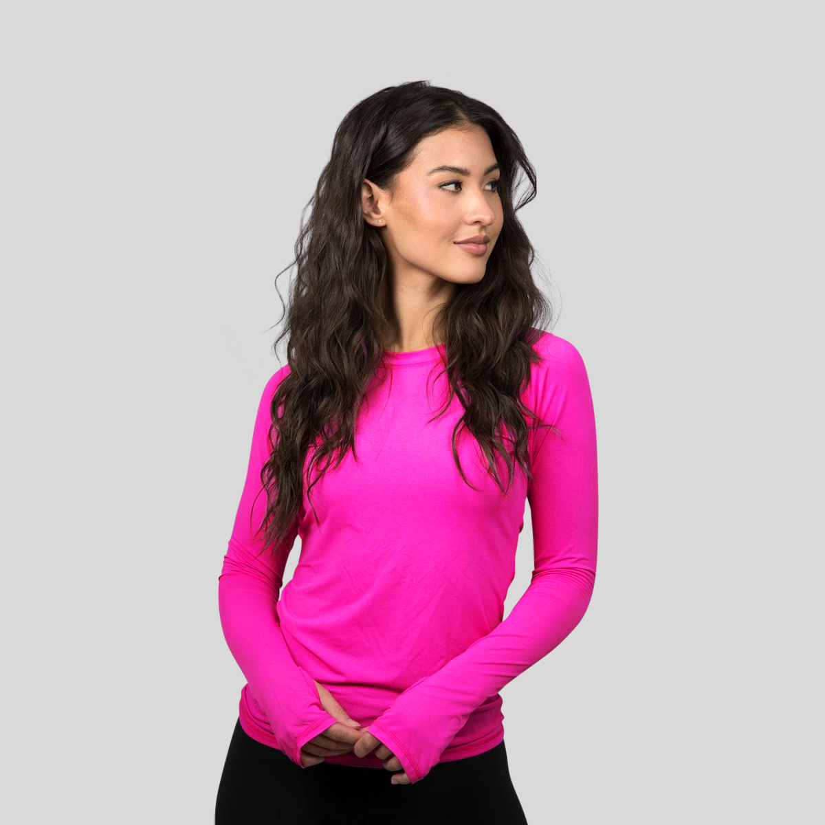 Woman wearing a bright pink long-sleeve top against a gray background