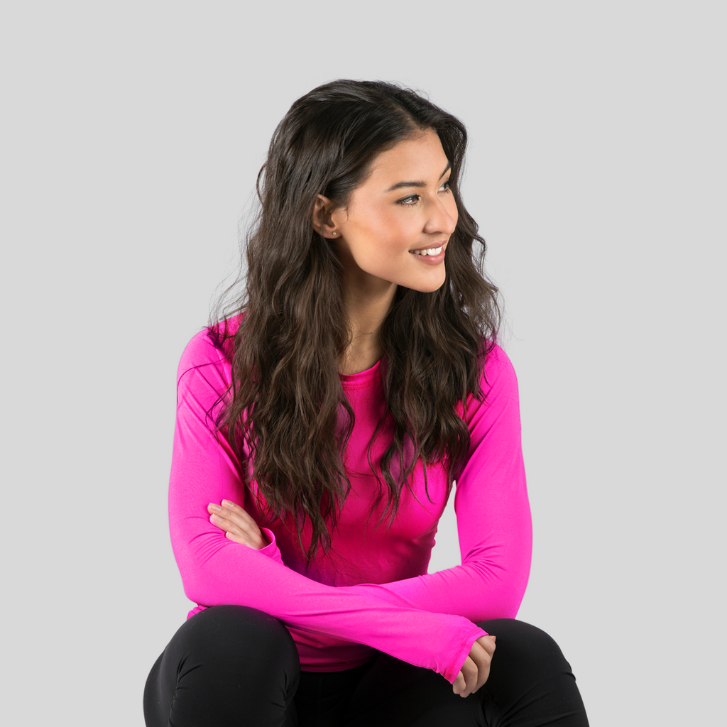 Woman wearing a bright pink long-sleeve top against a gray background