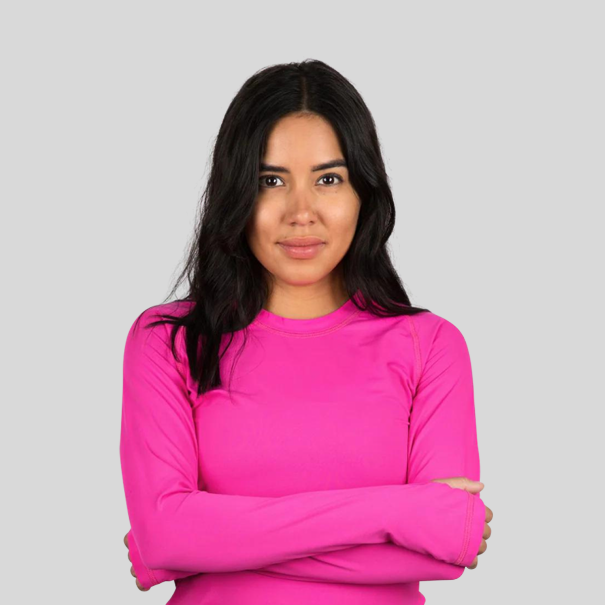 Woman wearing a bright pink long-sleeve shirt against a gray background