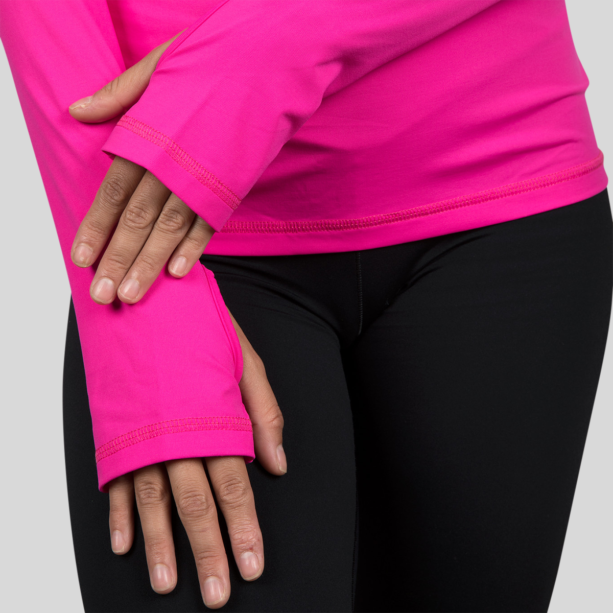Person wearing a bright pink long-sleeve shirt with black pants on a light gray background