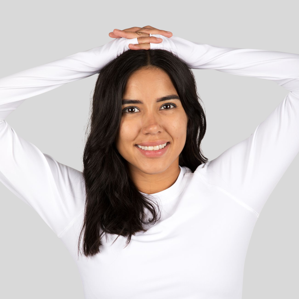 Woman wearing a white long-sleeve shirt against a plain background