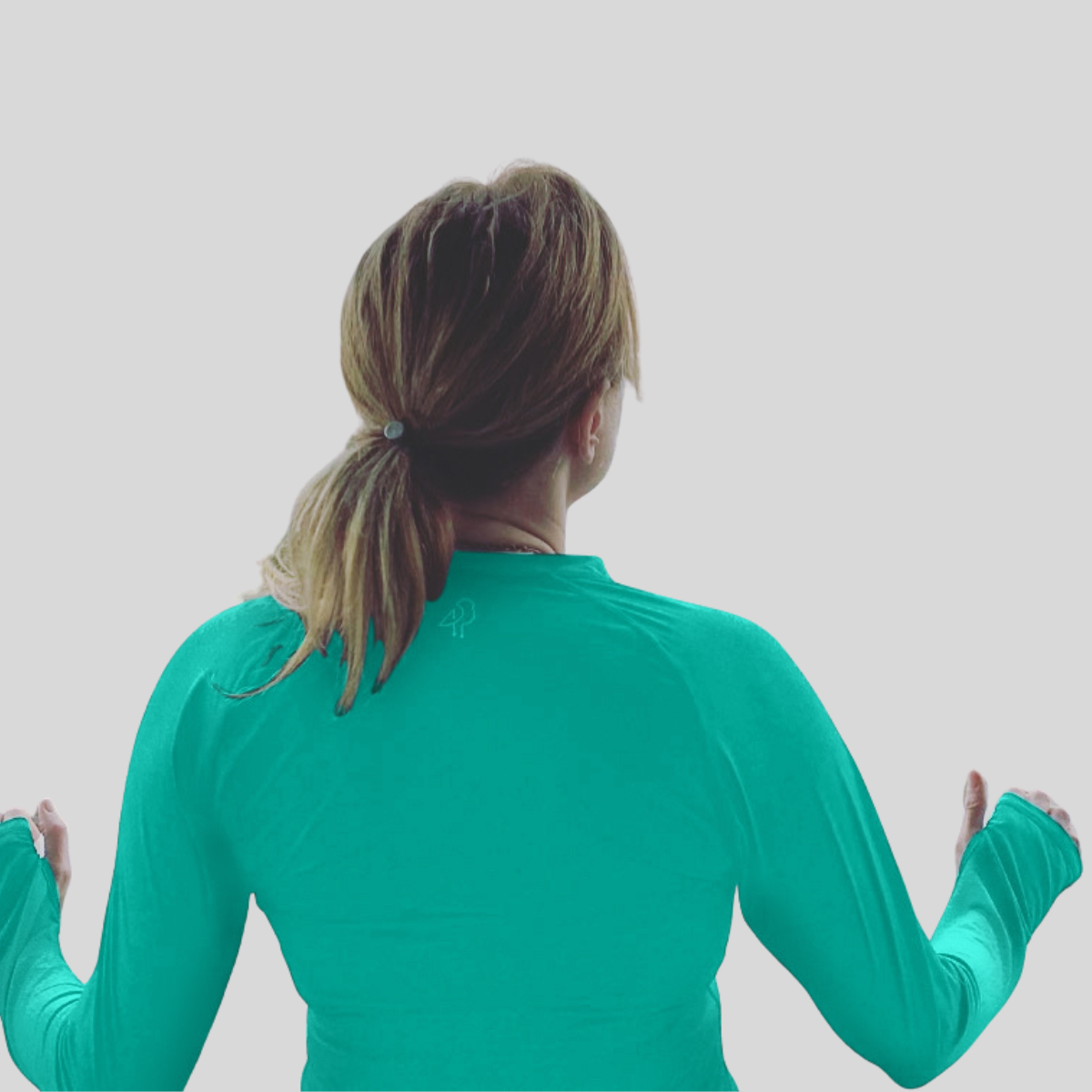 Person wearing a teal long-sleeve shirt against a light gray background
