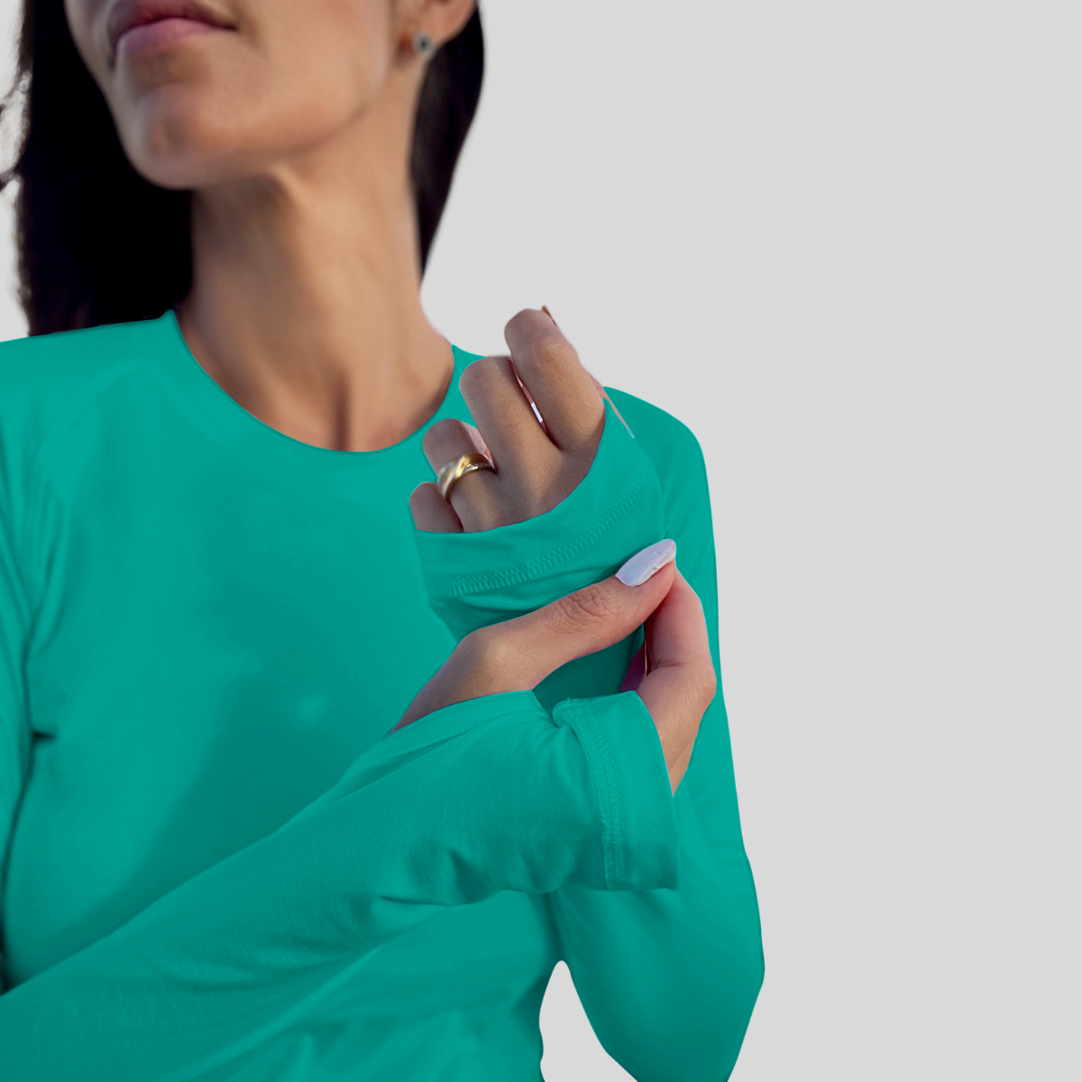 Person wearing a teal long-sleeve shirt with a plain background