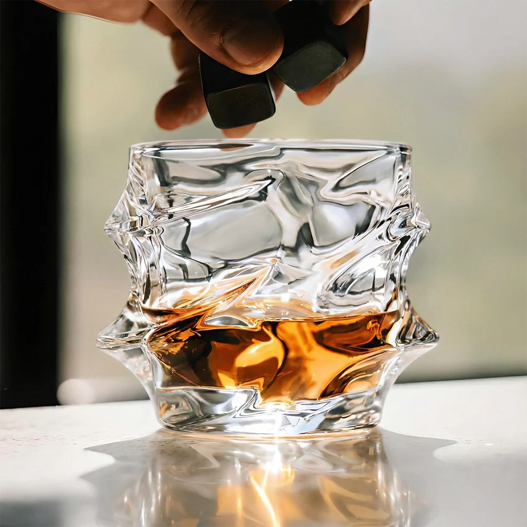 Crystal glass filled with whiskey being filled by a hand using a decanter.