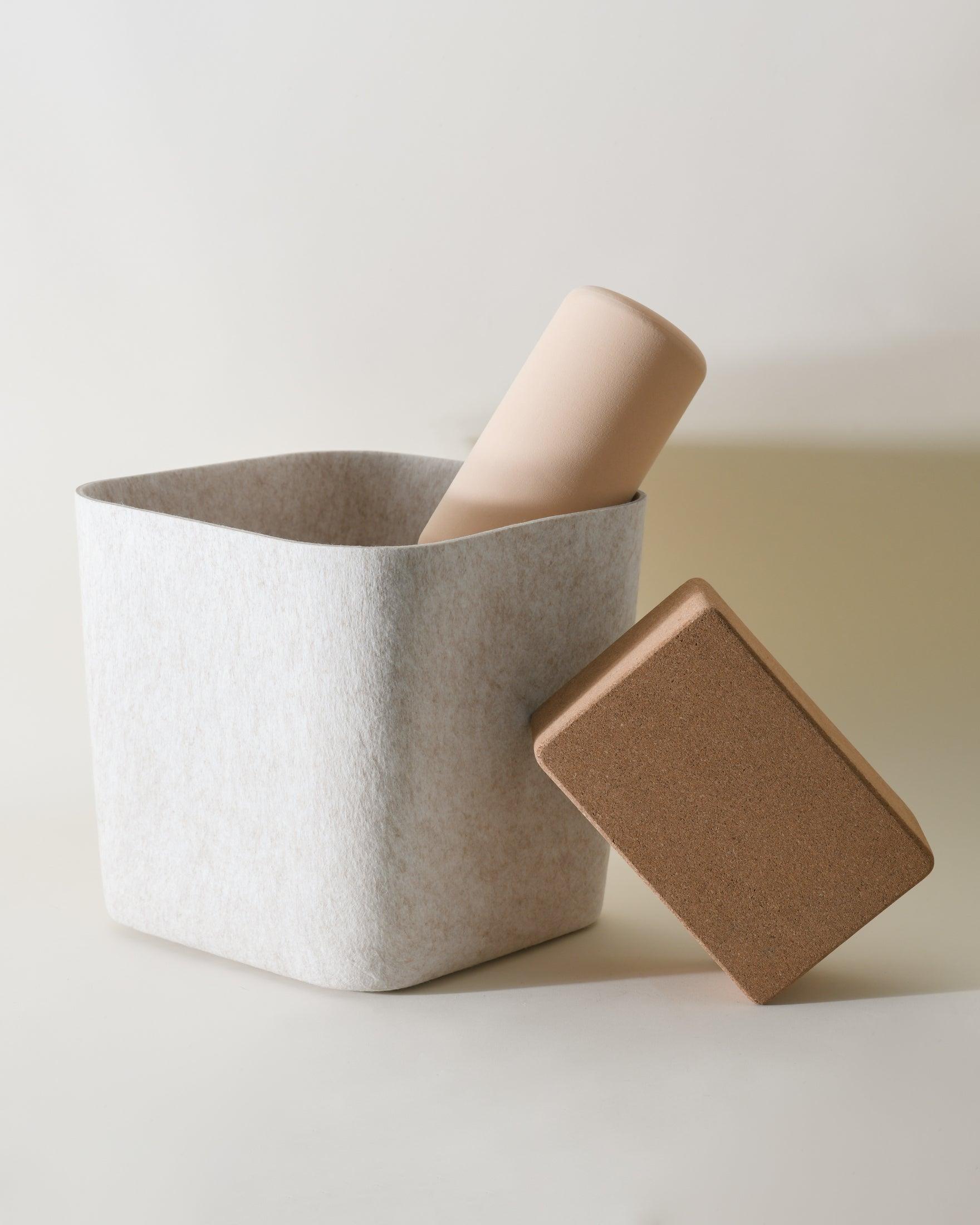 Square gray container with a cylindrical beige object and a square brown object on a light background