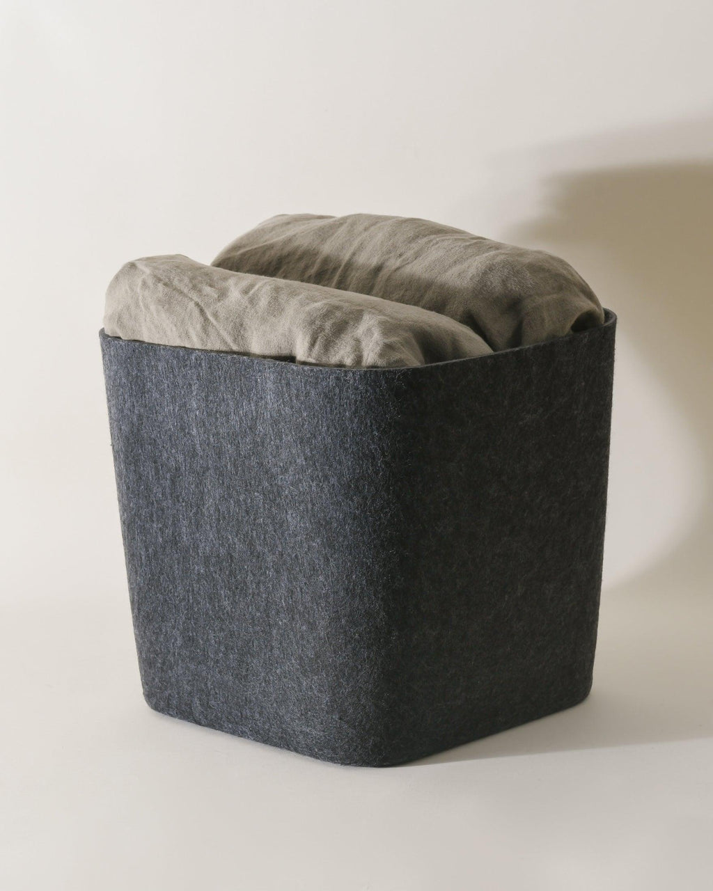 Dark gray ottoman with a cushion on a light background