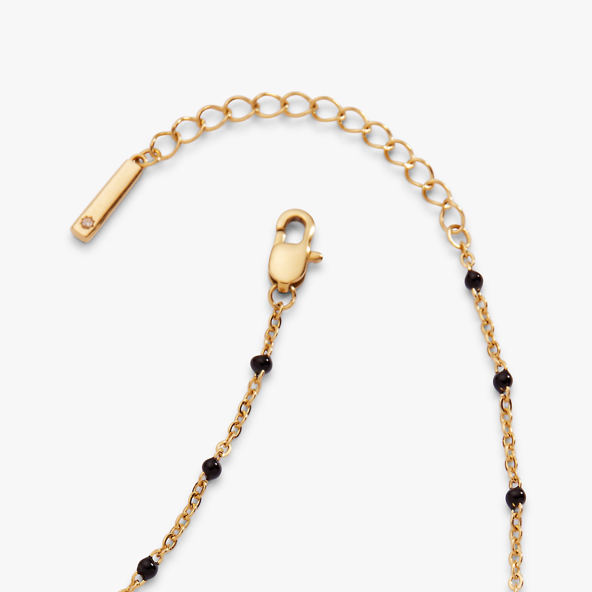 Gold chain necklace with black beads on a white background