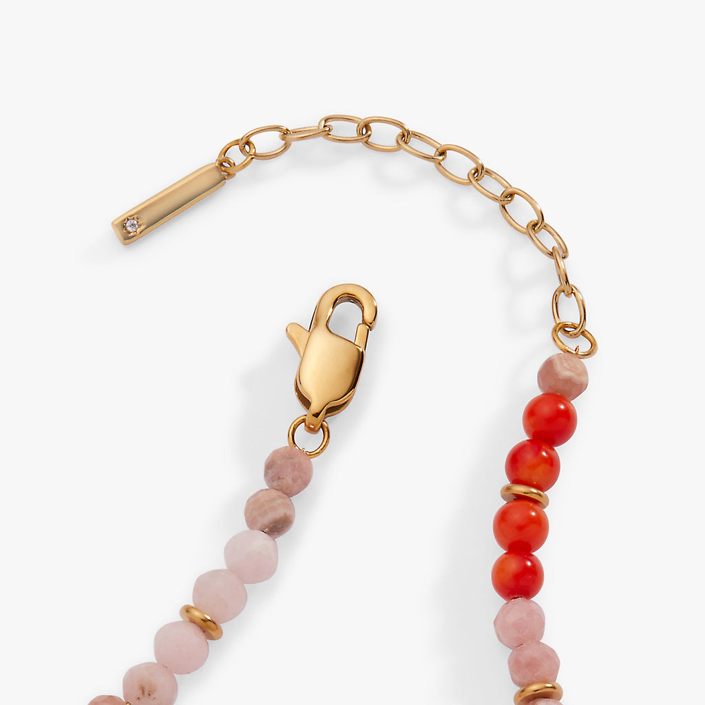 Bracelet with gold clasp, pink and red beads on a white background