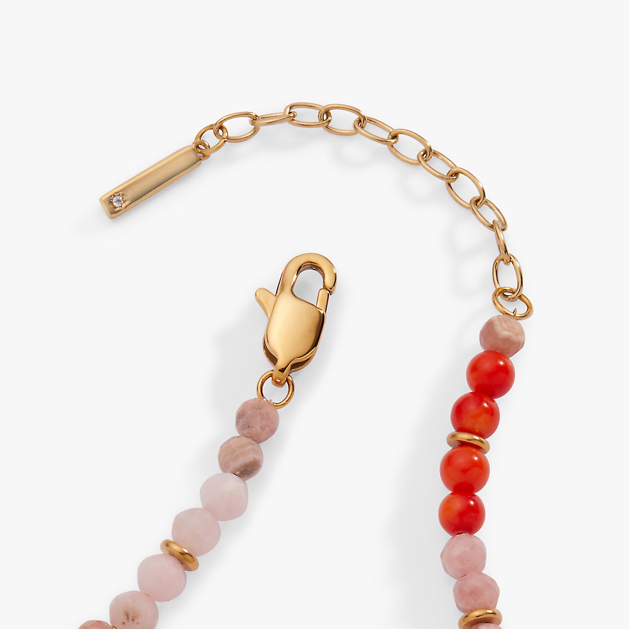 Bracelet with gold clasp, pink and red beads on a white background