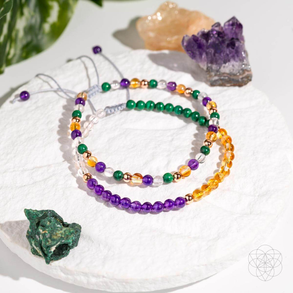 Set of colorful beaded bracelets on a white surface with crystals around