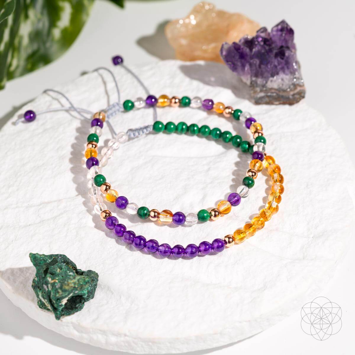 Set of colorful beaded bracelets on a white surface with crystals around