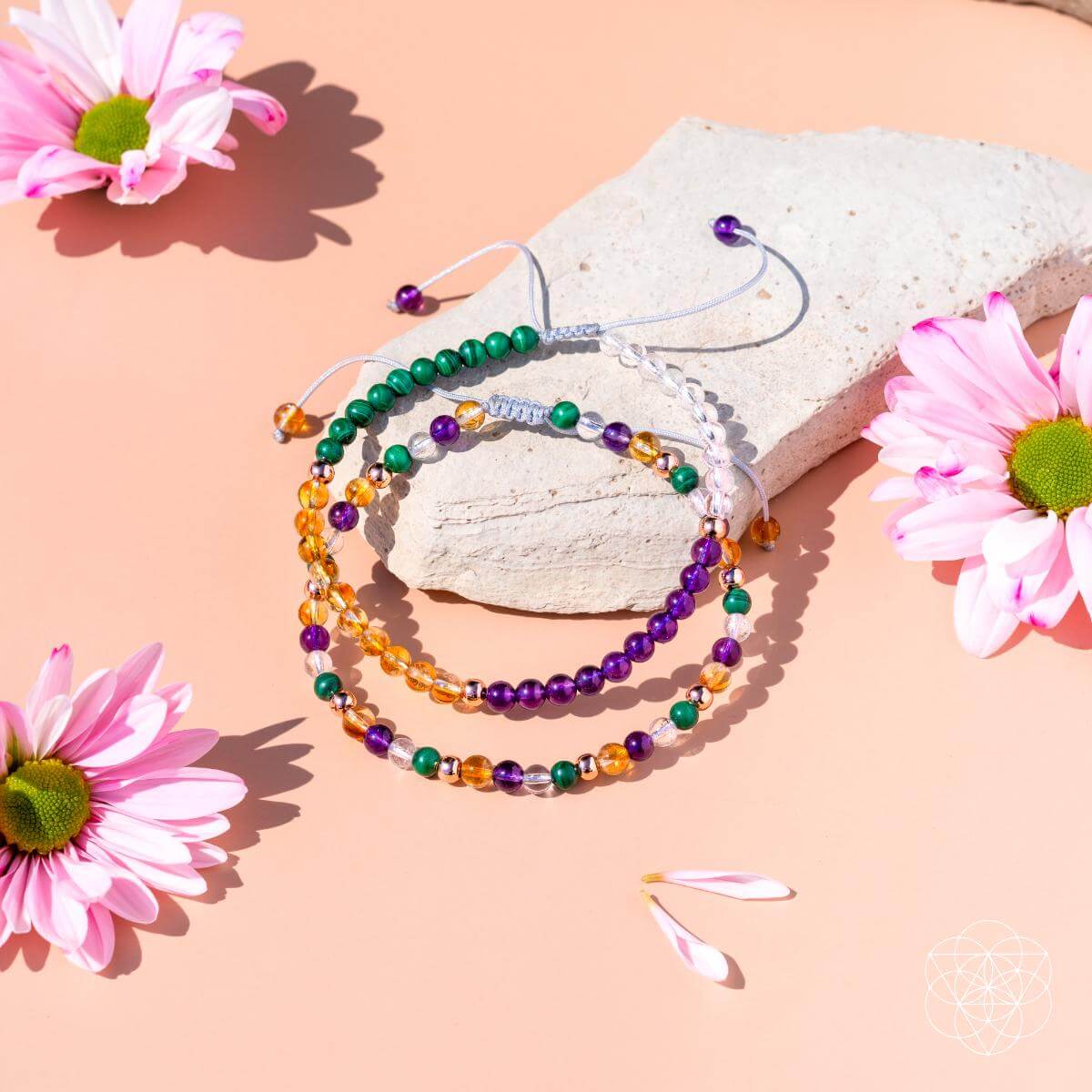 Colorful beaded bracelets on a pink surface with pink flowers