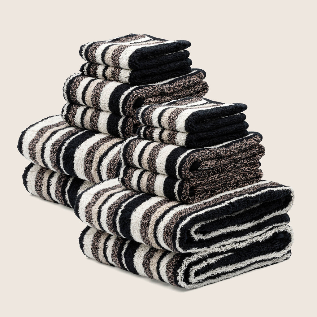 Stack of black and white striped towels on a beige background