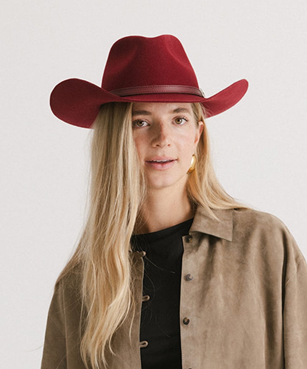 Person wearing a red cowboy hat against a plain background