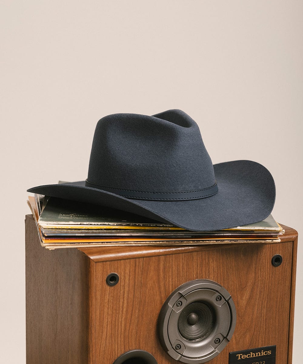 Black cowboy hat on a Technics record player with vinyl records.