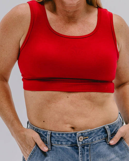 Person wearing a red tank top and blue jeans on a plain background