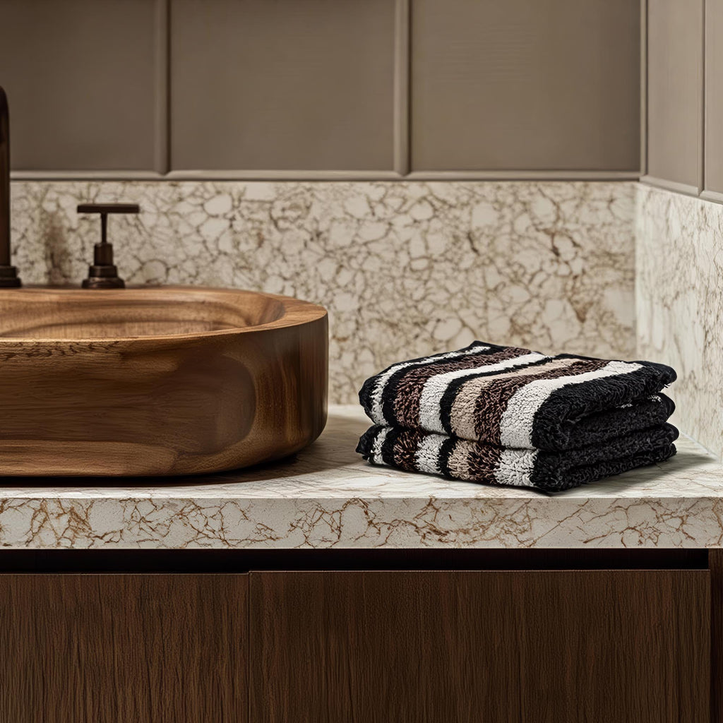 Wooden sink with striped towels on a marble countertop in a bathroom setting