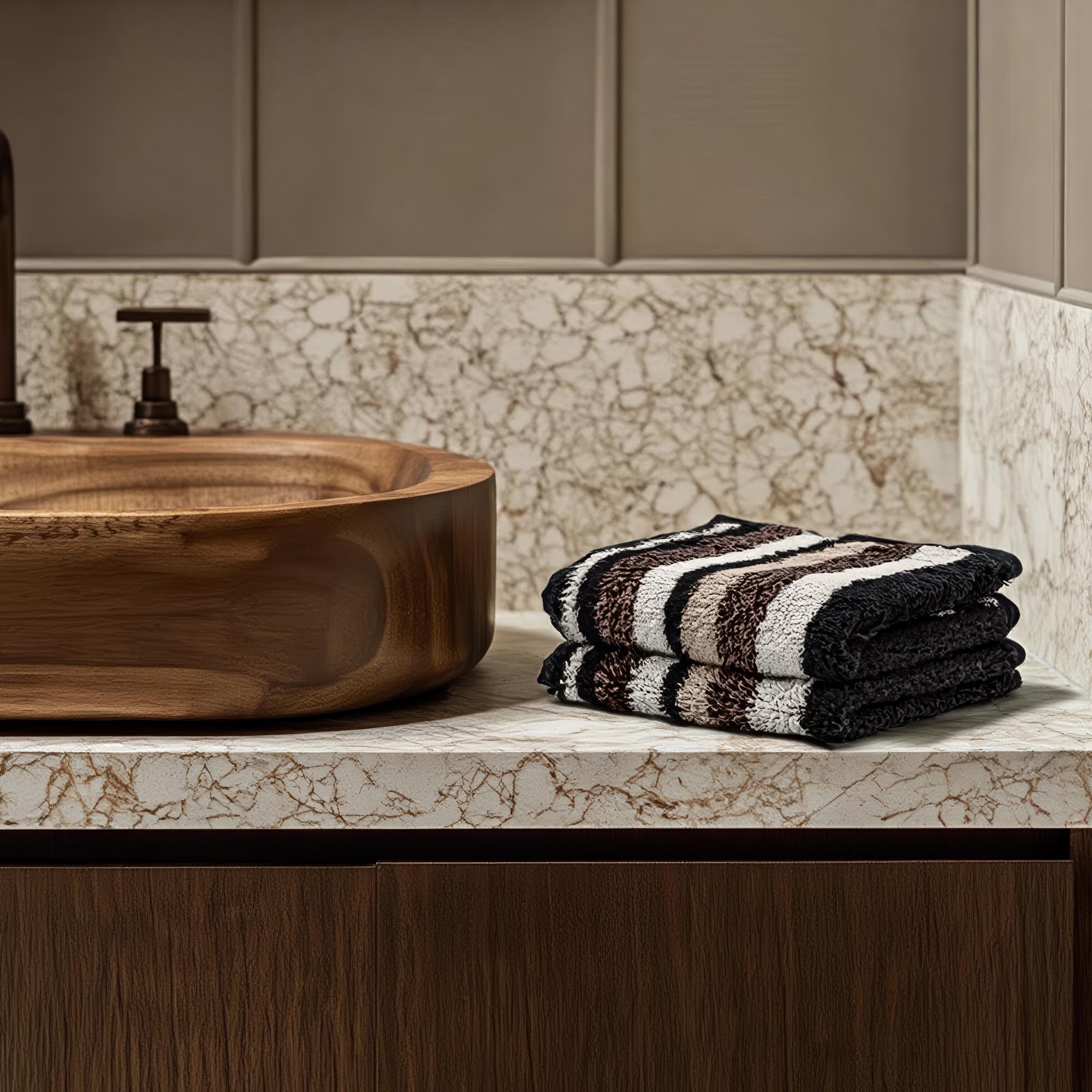 Wooden sink with striped towels on a marble countertop in a bathroom setting