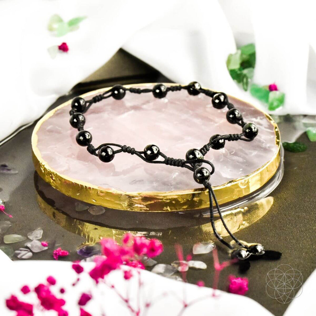 Black beaded necklace on a pink crystal with decorative background