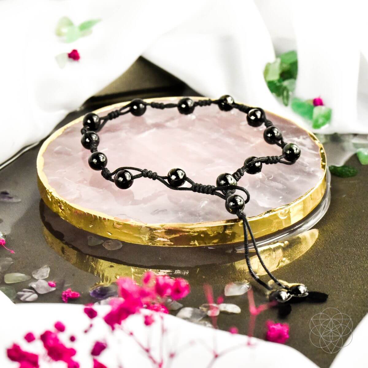 Black beaded necklace on a pink crystal with decorative background