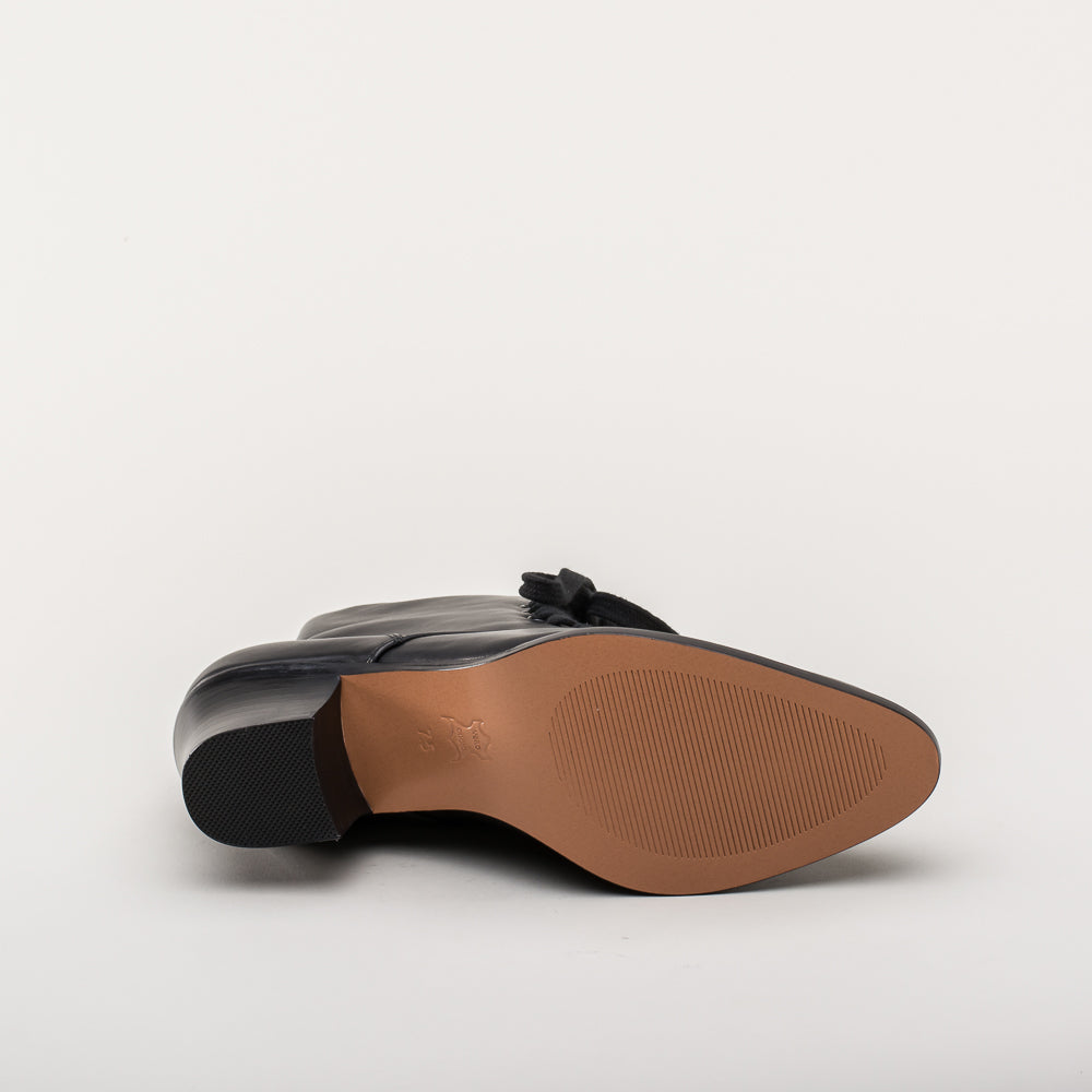 Black shoe with brown sole on a light gray background