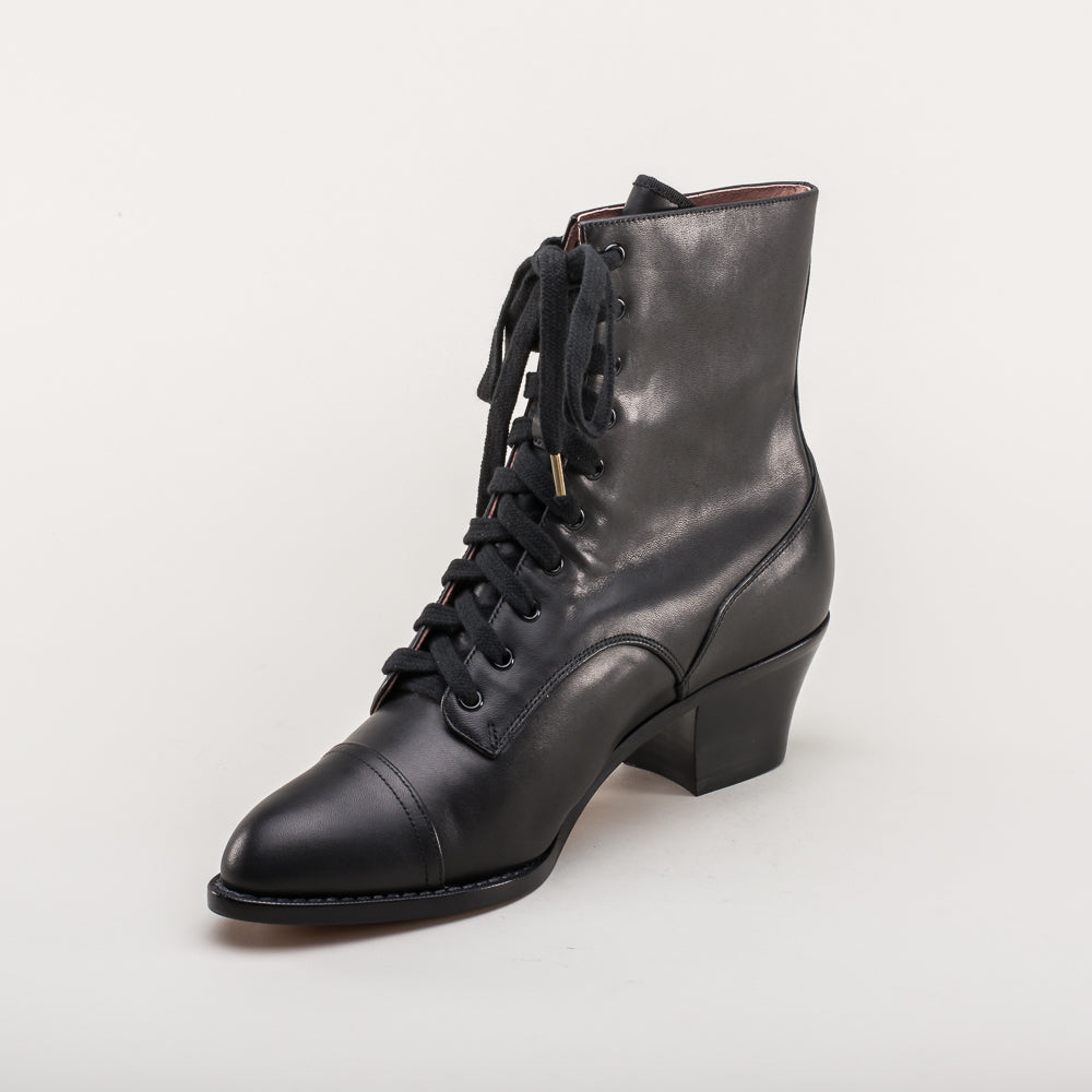 Black leather boot with laces on a light gray background