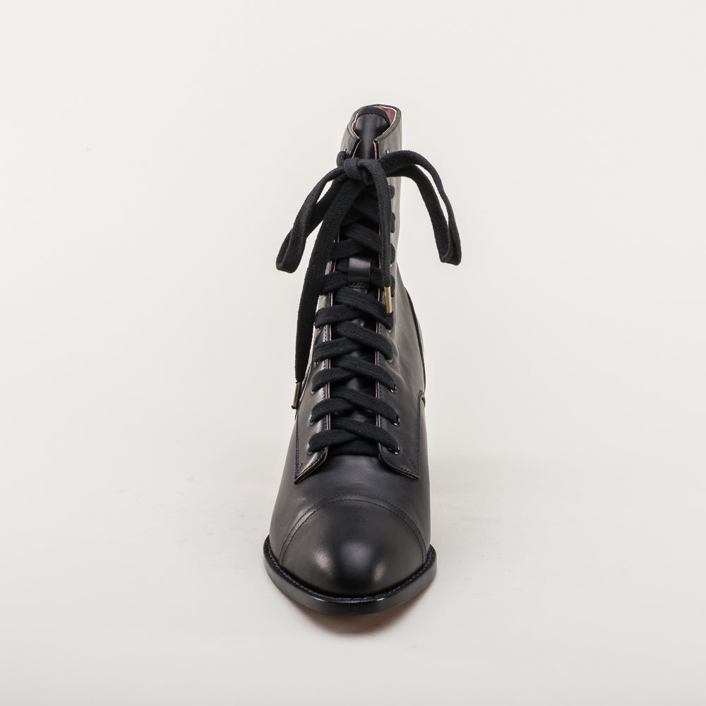 Black leather boot with laces on a light gray background