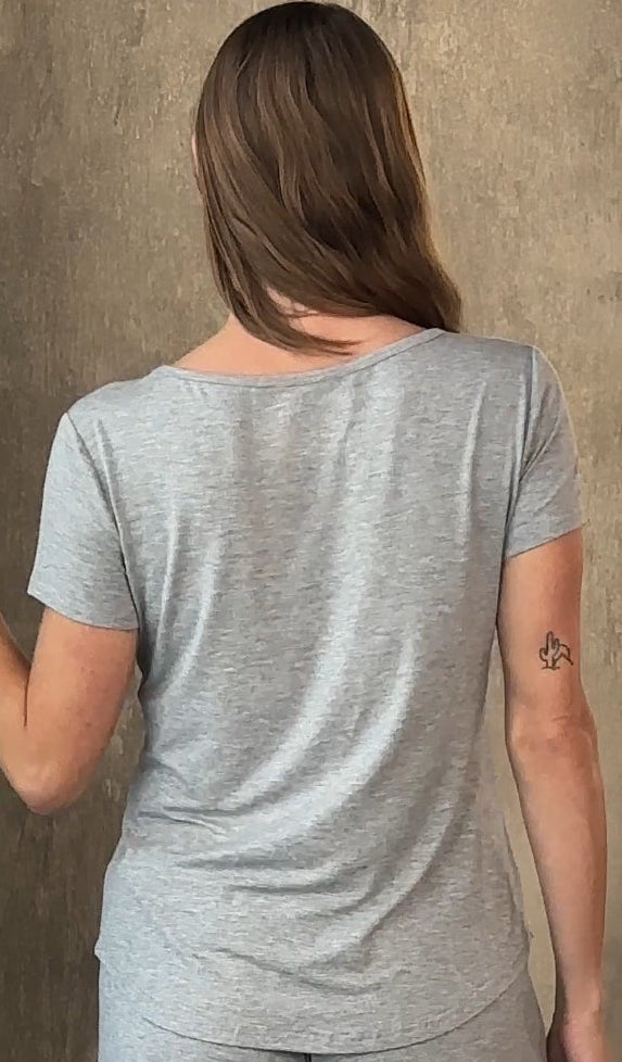Person wearing a gray t-shirt against a textured wall