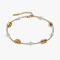 Gold bracelet with pearls and shell-shaped beads on a white background