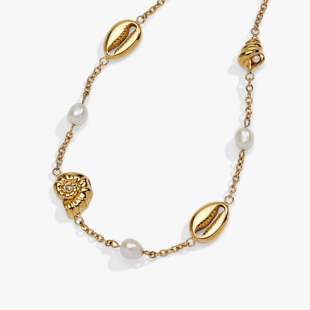 Gold necklace with shell and pearl accents on a white background