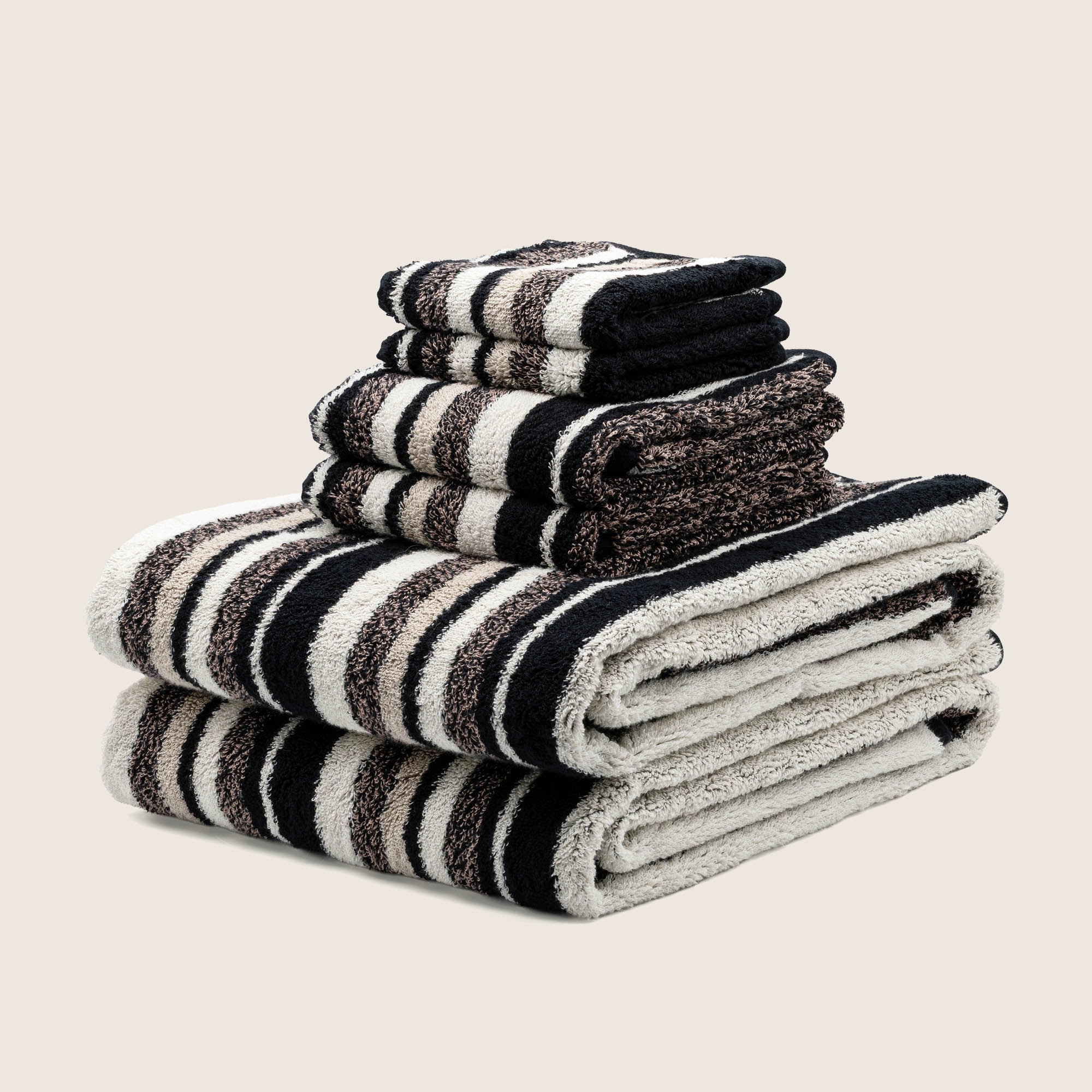 Stack of black and white striped towels on a beige background
