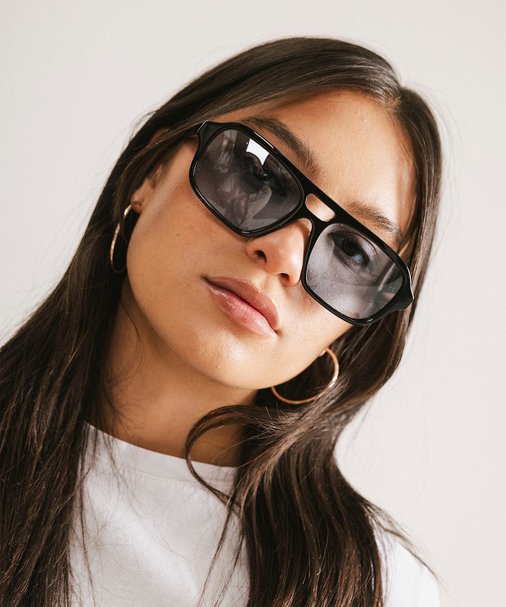 Woman wearing black sunglasses with a neutral background