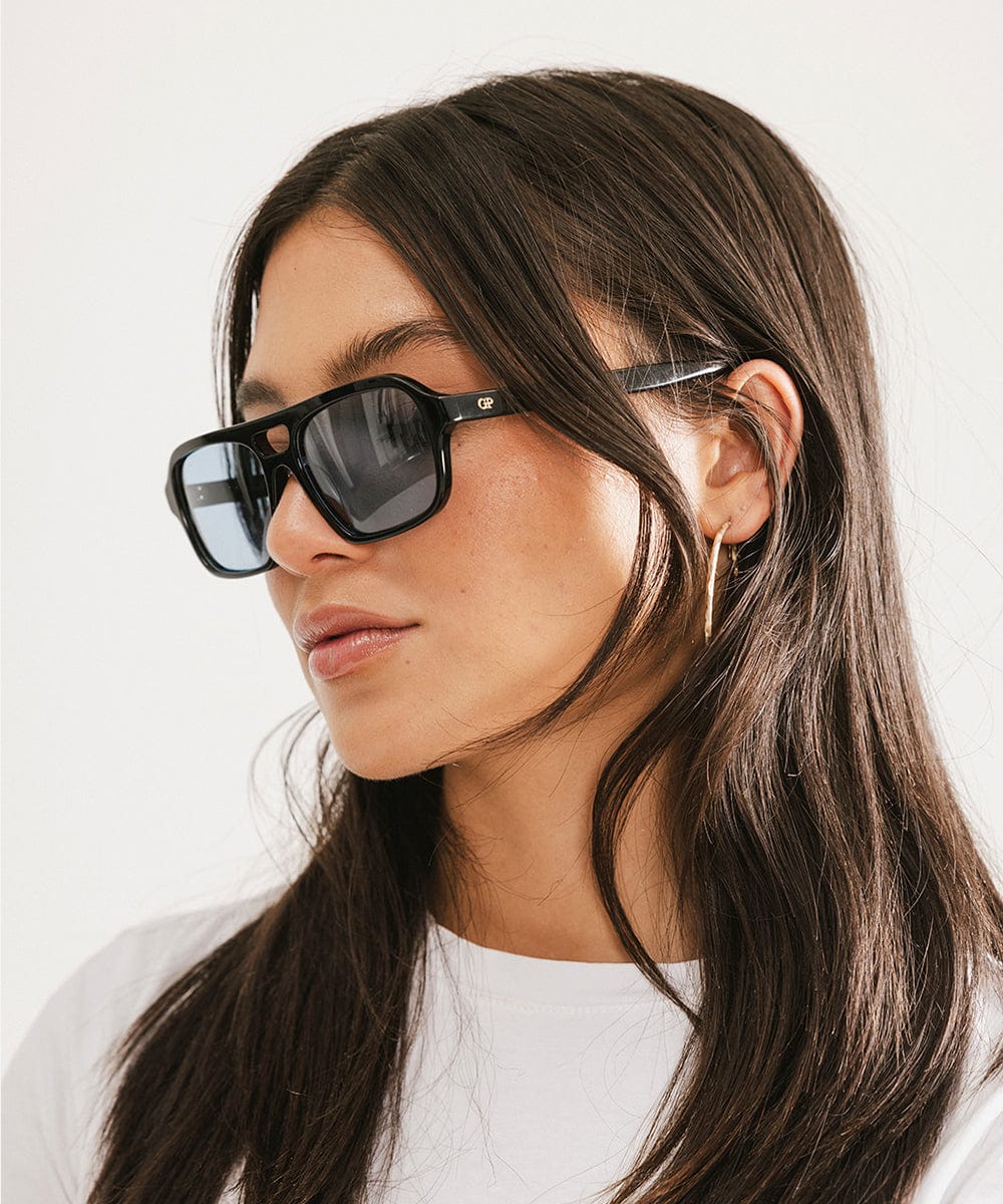 Woman wearing black sunglasses with a plain white background