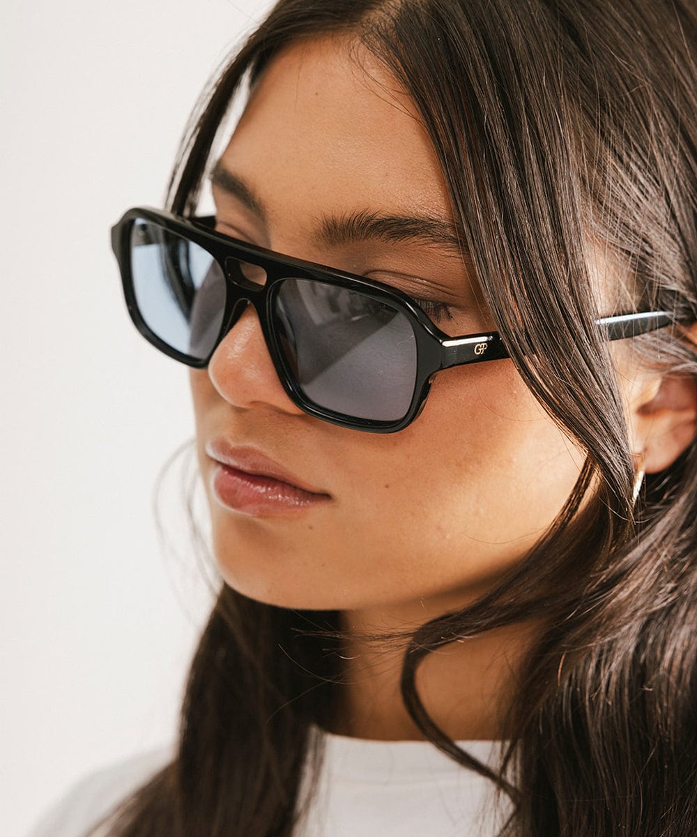 Close-up of a person wearing black sunglasses with a neutral background